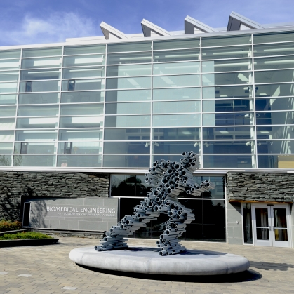 Sculpture made from pipes to mimic a running man in front of a biomedical engineering four-story building 