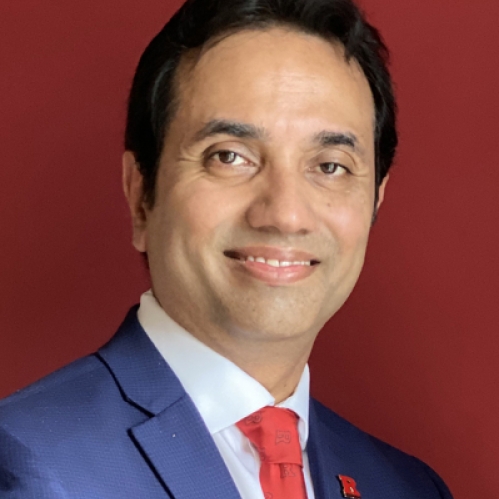 Head shot of Asian male with short black hair wearing a blue suit jacket, a white button down shirt, and a red tie.