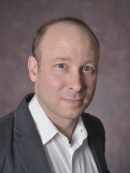 head shot of man wearing a grey suit jacket and white button down shirt