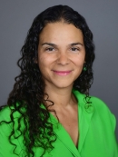 head shot of woman with long curly black hair wearing a bright green blouse
