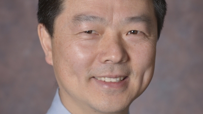 head shot of asian male with short black hair wearing a light blue shirt with a gold tie