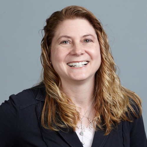 head shot of female with long dark blonde hair wearing a dark suit jacket with a white shirt