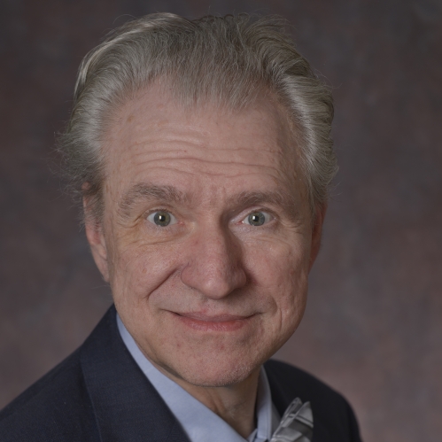 head shot of male with short grey hair wearing a dark blue suit, light blue shirt, and bow tie