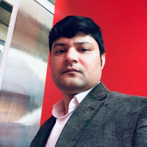 Headshot of Indian male with short, black hair, wearing a grey suit jacket with a pink button down shirt.