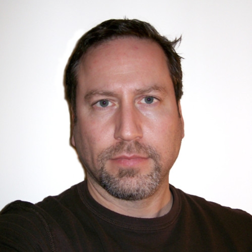 Headshot of male with short brown hair, wearing a black pullover sweater.