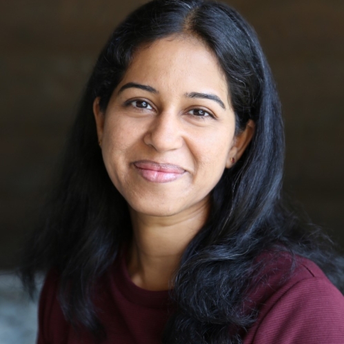 Headshot of smiling woman with long black hair wearing a burgundy top.
