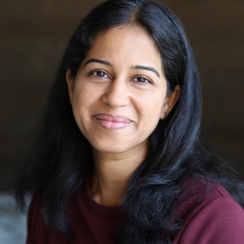 Headshot of woman with long black hair wearing a burgundy top. She is smiling.