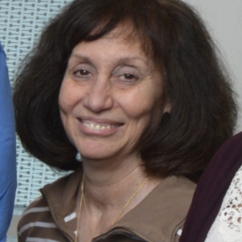 Head shot of woman with shoulder length brown hair and bangs wearing a brown and white stripped sweater.