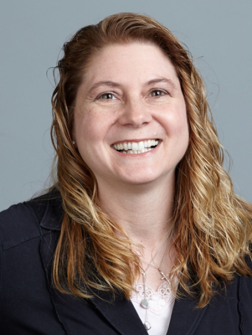 head shot of female with long dark blonde hair wearing a dark suit jacket with a white shirt