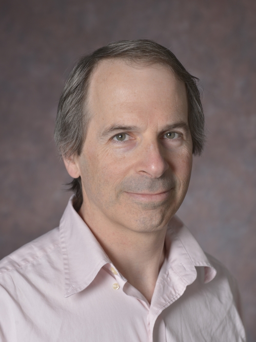 head shot of man with light brown hair wearing a light pink button down shirt