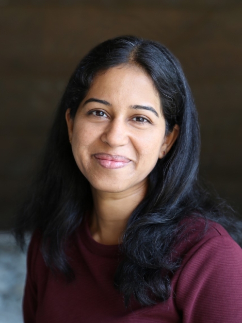 Headshot of woman with long black hair wearing a burgundy top. She is smiling.