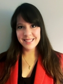 head shot of woman with long brown hair and bangs wearing a red suit jacket with a black blouse