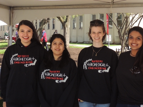 four young women standing side-by-side outdoors wearing a black Rutgers Biomedical Engineering sweatshirts