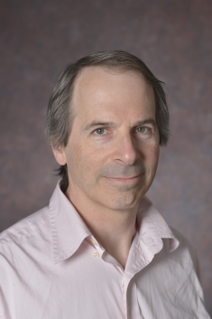 head shot of man with light brown hair wearing a light pink button down shirt